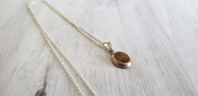 Load image into Gallery viewer, Vintage small oval tiger eye sterling silver  pendant on 18&quot; 925 silver chain, Gray Barn Eclectic Finds online vintage store, flat on table, shows side stepped profile of pendant