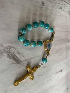 Group of vintage rosaries and chaplets on white wood background, Gray Barn Eclectic Finds online vintage store, teal and aqua blue marbled bead chaplet with gold tone findings