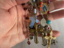 Load image into Gallery viewer, Group of vintage rosaries and chaplets on white wood background, Gray Barn Eclectic Finds online vintage store, held in hand