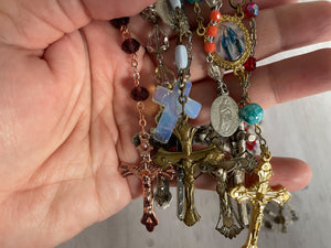 Group of vintage rosaries and chaplets on white wood background, Gray Barn Eclectic Finds online vintage store, held in hand