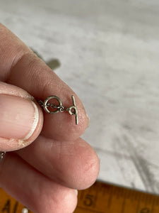 a close up of the ring and bar closure on the silver chain necklace (there is no way for the pendant to slip  off the chain easily with this type of closure)